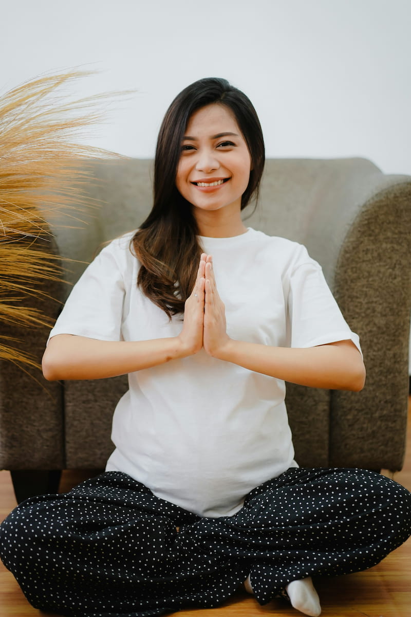young expecting mother smiling in a sitting yoga pose